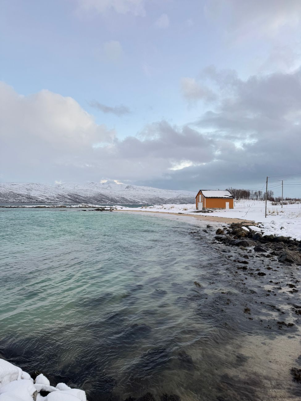 Panoramic view of Scandinavian timber shelter over dark fjord waters